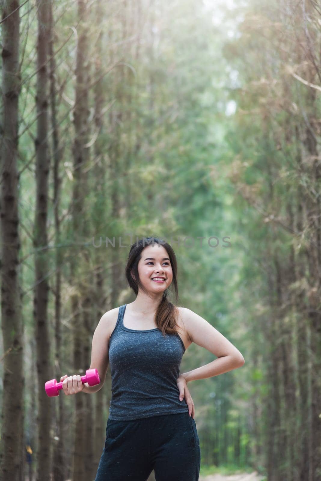 Beautiful sport young female woman lifestyle relaxation dumbbell workout in forest nature park with copy space