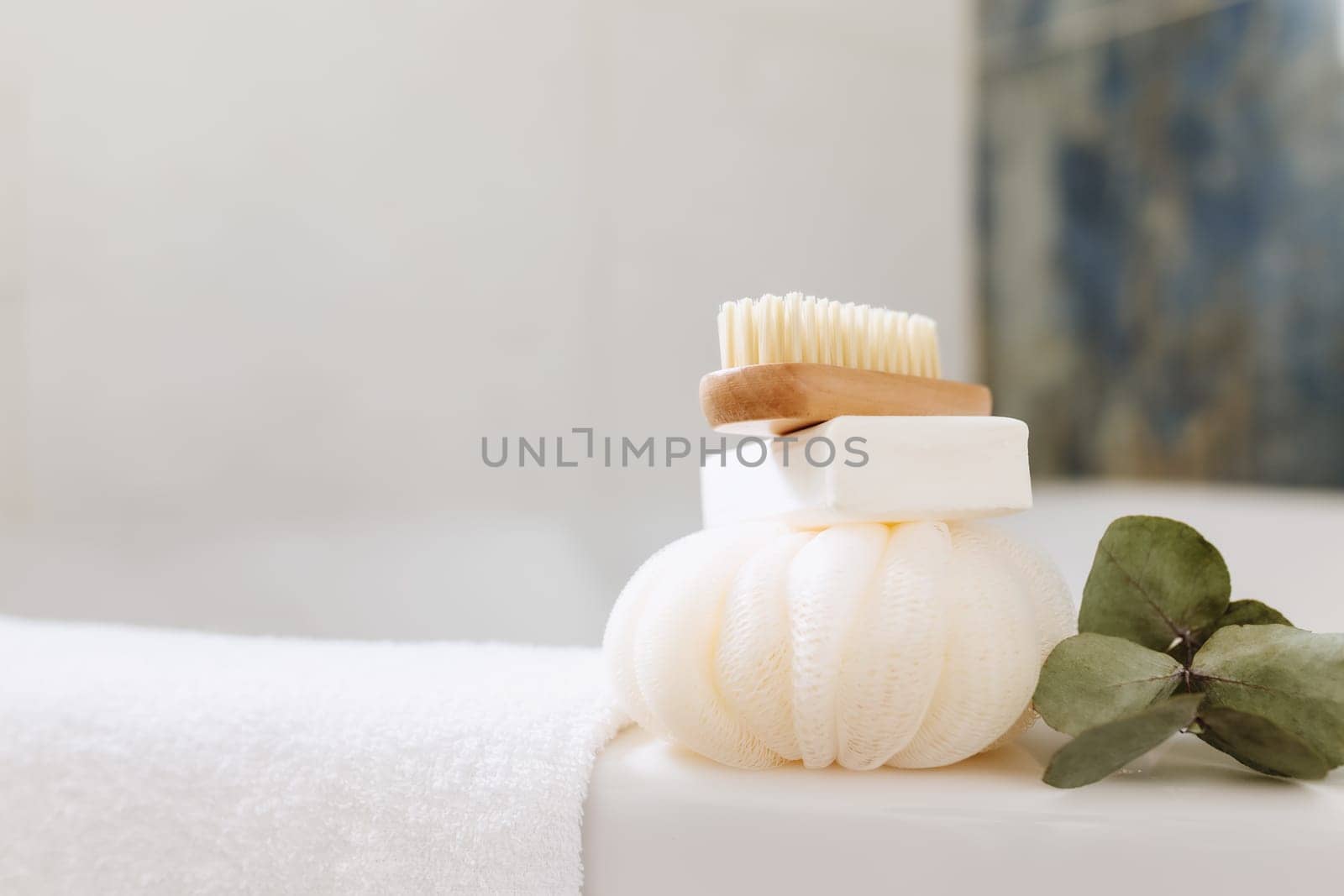 Washbasin in white bathroom with bath accessories. Hotel cleaning concept. Household concept. Washcloth, soap, foot brush, white towel and eucalyptus branch with green leaves. Stylish bathroom