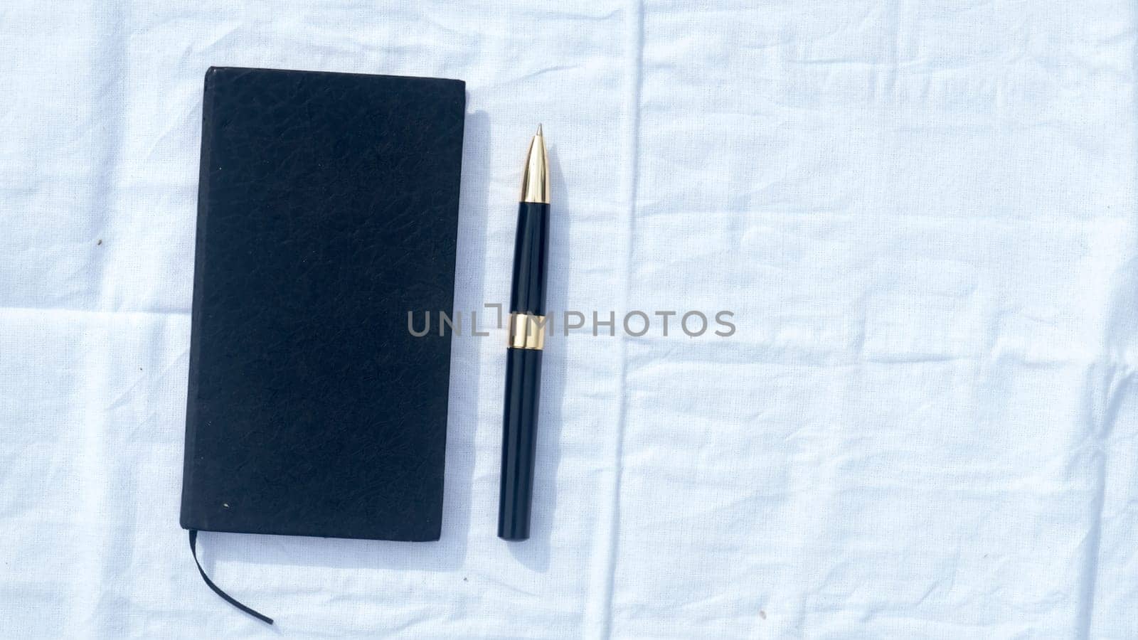 A notebook and a pen on white cotton cloth. High angel view. Business Education background. Copy space room for text on right side.