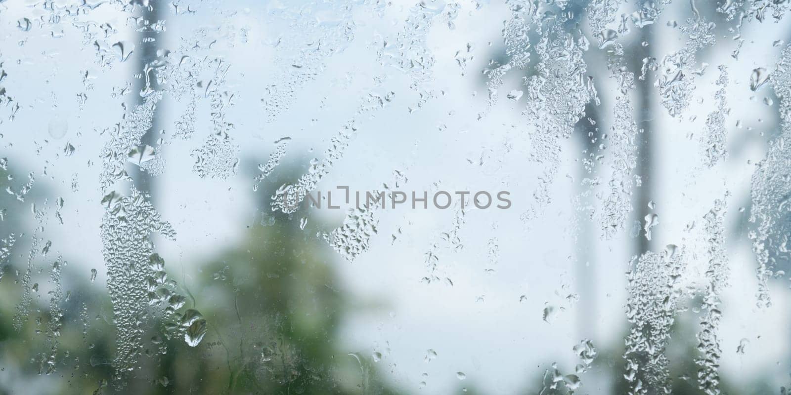 Rain drops on glass window. Raindrops falling from glass material. Abstract nature background. Copy space for text. Focus on foreground.