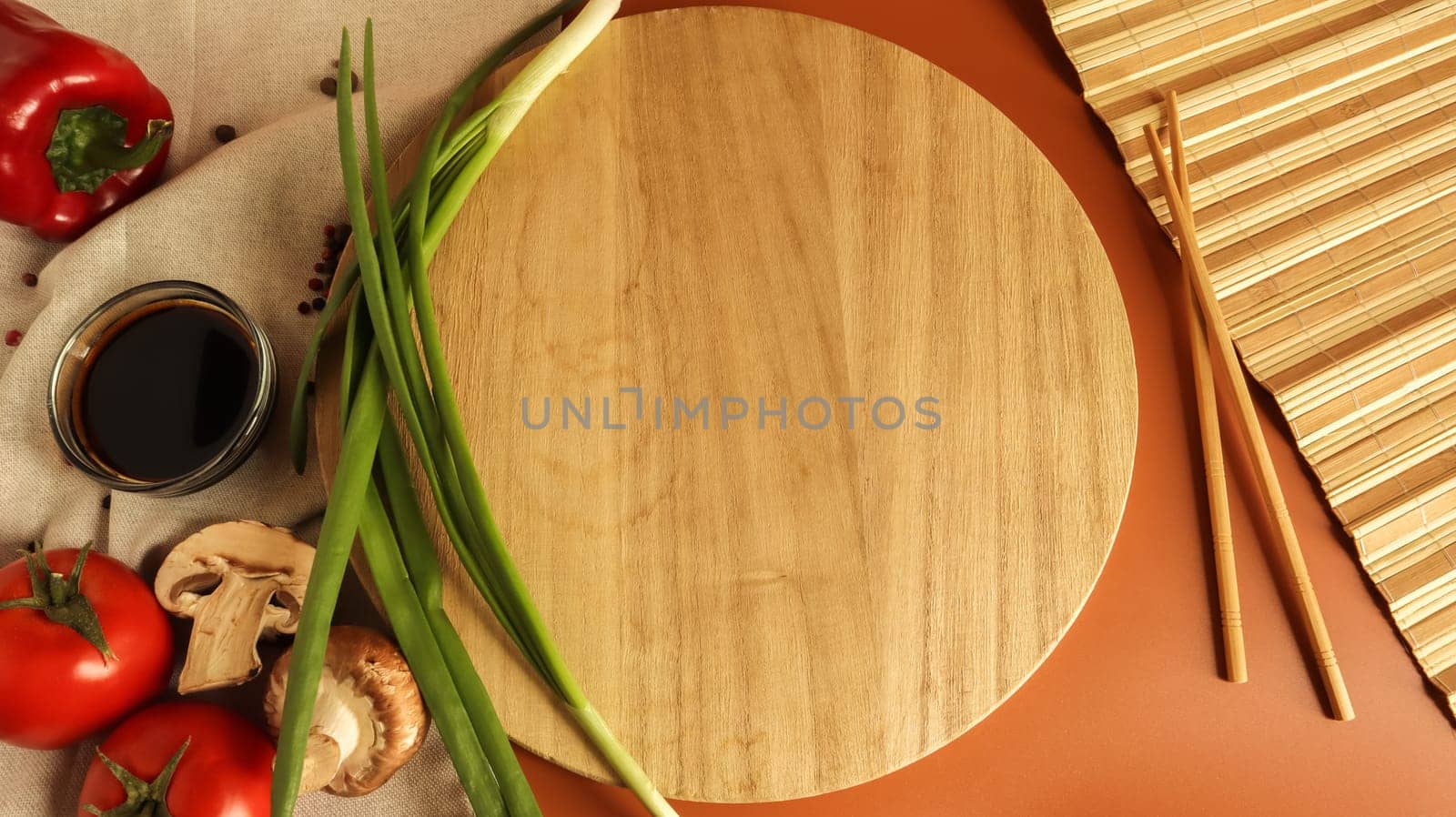 Round wooden board, sauce and various vegetables on the table, wooden stick on a brown background. Flat lay. Copy space in the center of the frame for your text or logo. Recipe and Cooking.