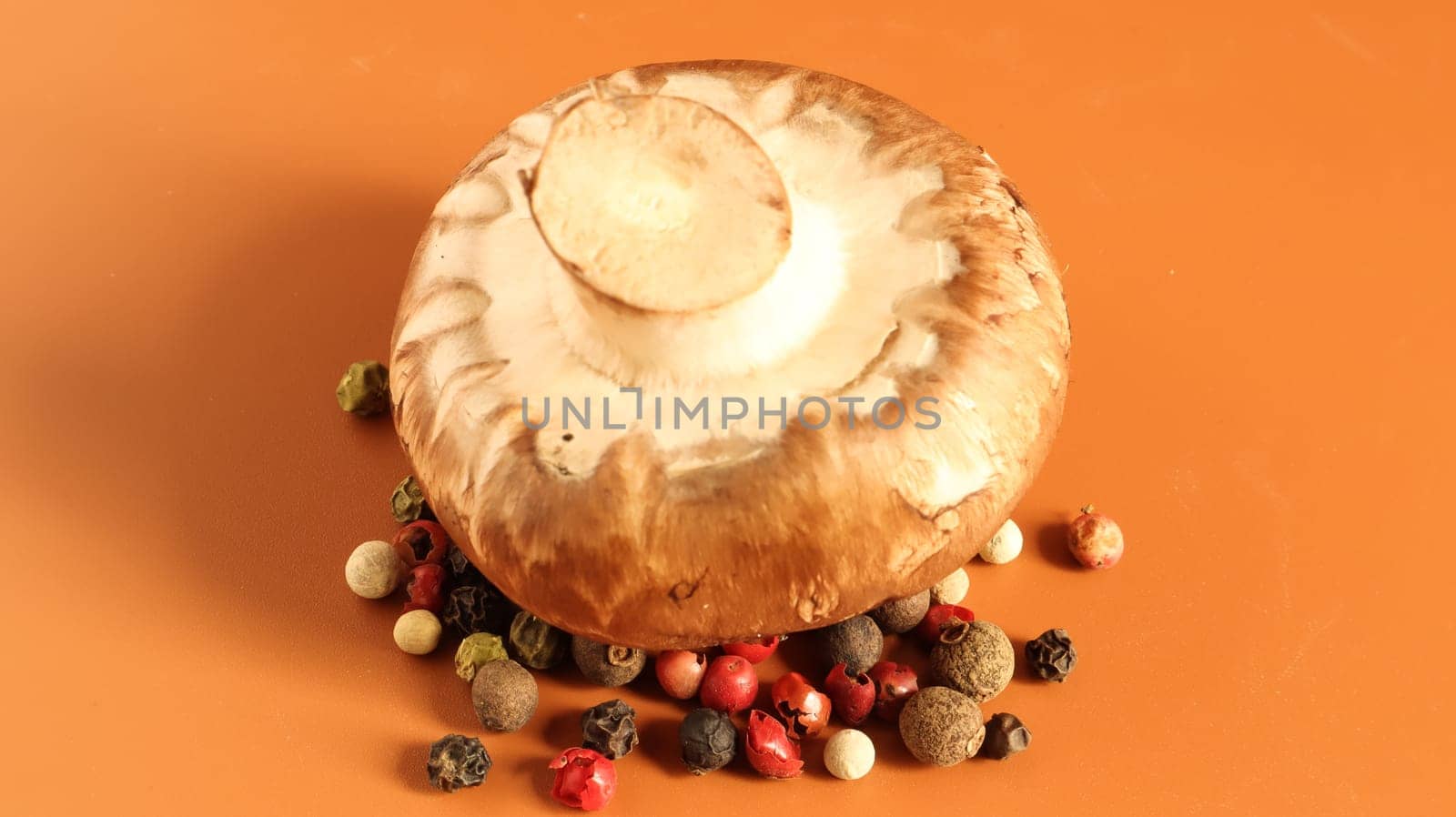 one brown royal champignon on a yellow background with a mixture of peppers. Such mushrooms resemble the taste of porcini mushrooms and have a more pronounced mushroom taste and smell