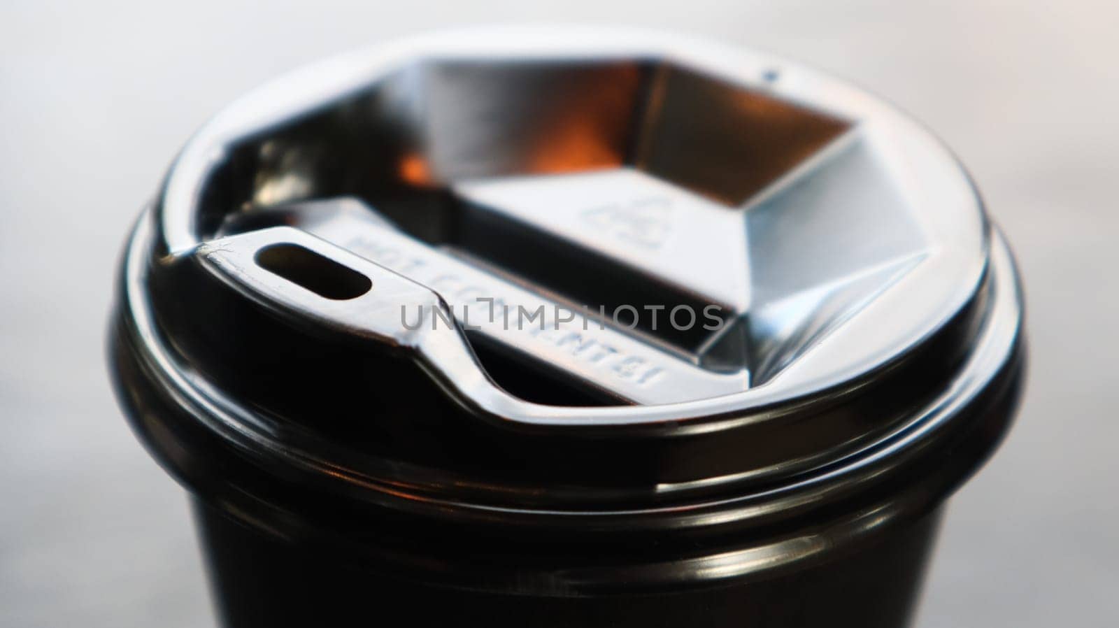 Black plastic coffee cup cover, top view. Takeaway coffee cup black background. Disposable cup close-up on a wooden table. Minimalist style.