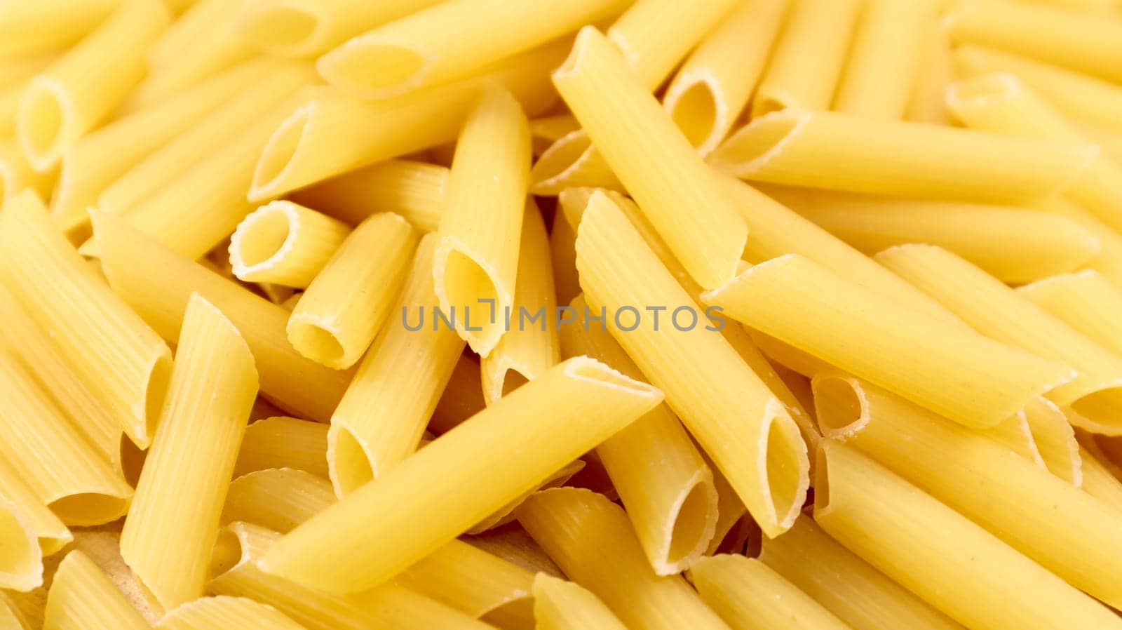 Penne Rigate Raw Pasta is a short pasta with oblique cuts and a ribbed surface. Traditional Italian pasta. Pasta background. Italian food ingredient top view