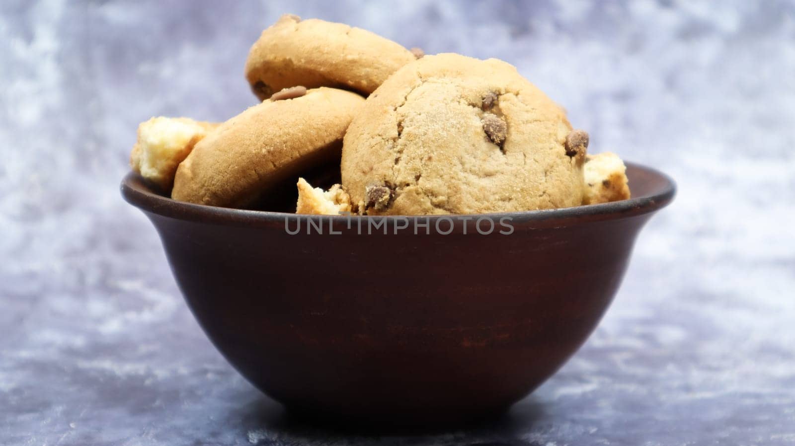 Soft freshly baked cookies with chocolate chips in a brown earthenware plate on gray marble. American traditional sweet pastry pastry, delicious homemade dessert. Culinary background