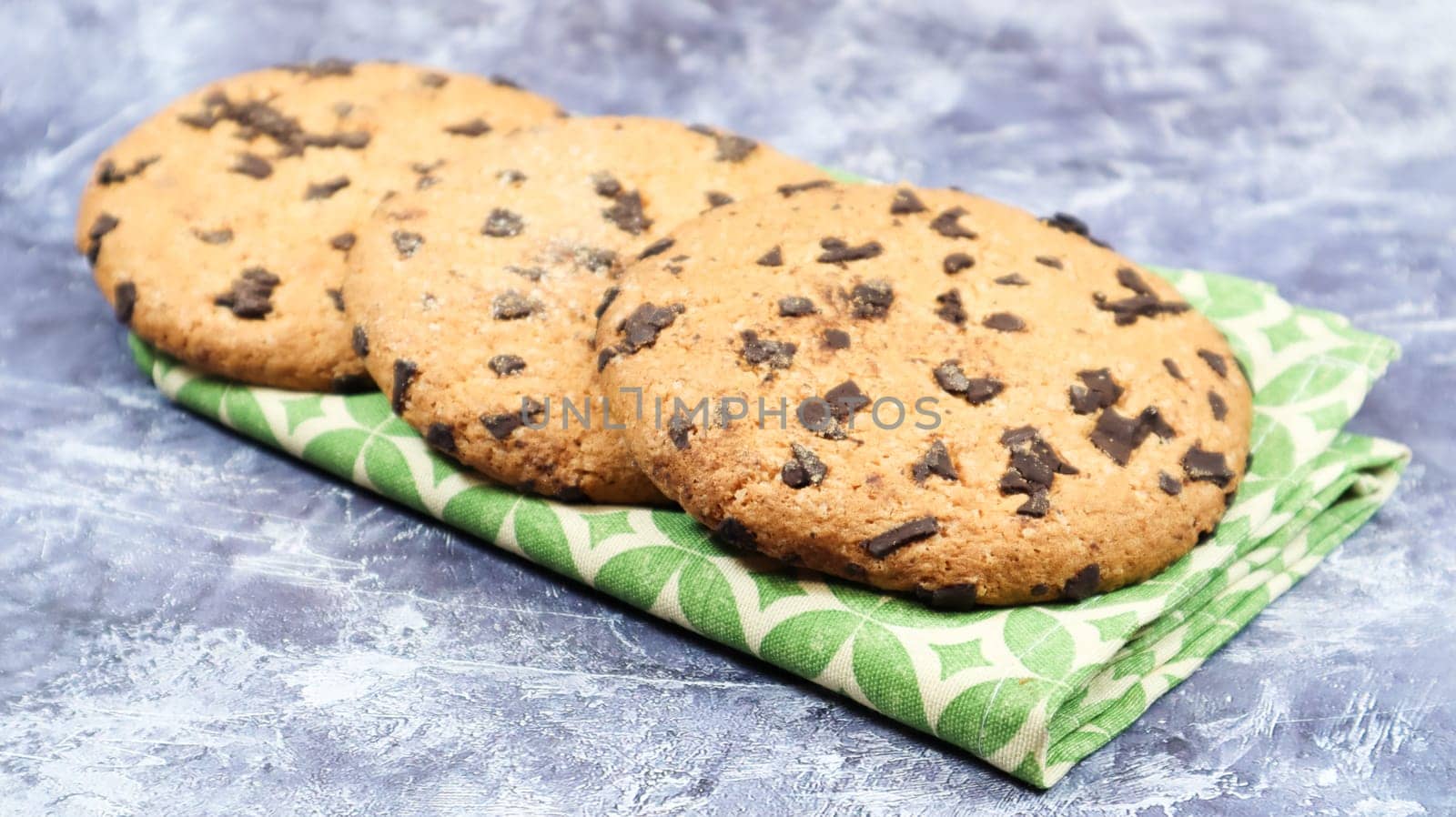 American chocolate chip cookies on a green napkin on a gray background. Traditional round crispy dough with chocolate chips. Bakery. Delicious dessert, pastries