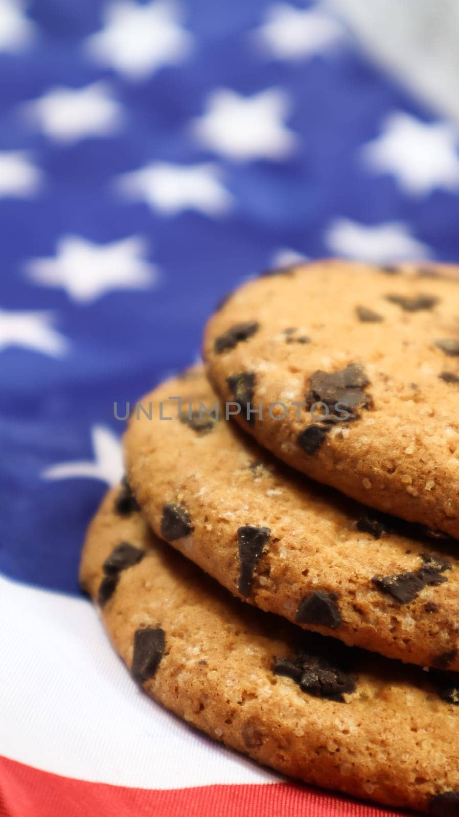 Patriotic cookies. Three rounded traditional chocolate chip cookies on the background of the flag of the United States of America. Delicious sweet pastries, dessert. America's favorite treat