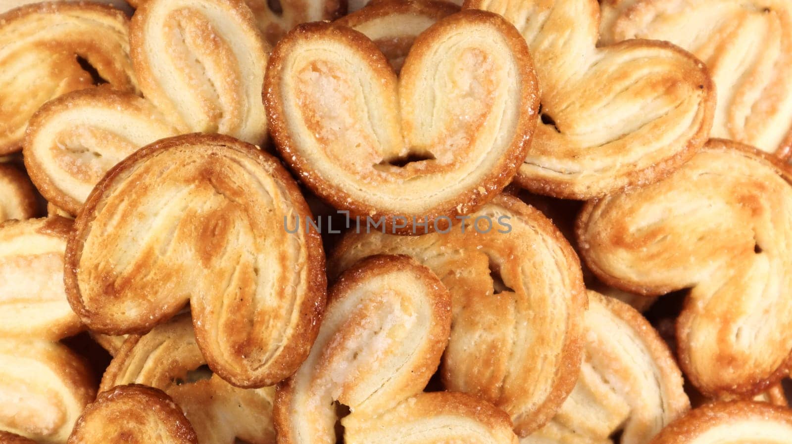Fresh puff pastry palm cookies in the shape of a heart. Classic French pastries. Pig ear, elephant ear cookies, French hearts. View from above.