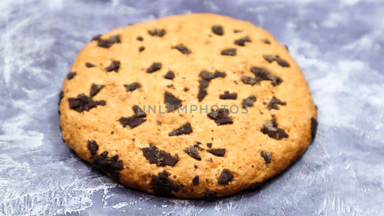 One soft, freshly baked chocolate chip cookie on a gray marble kitchen countertop. American traditional dessert. Delicious sweet food. Homemade baking concept for the holiday. Culinary background.