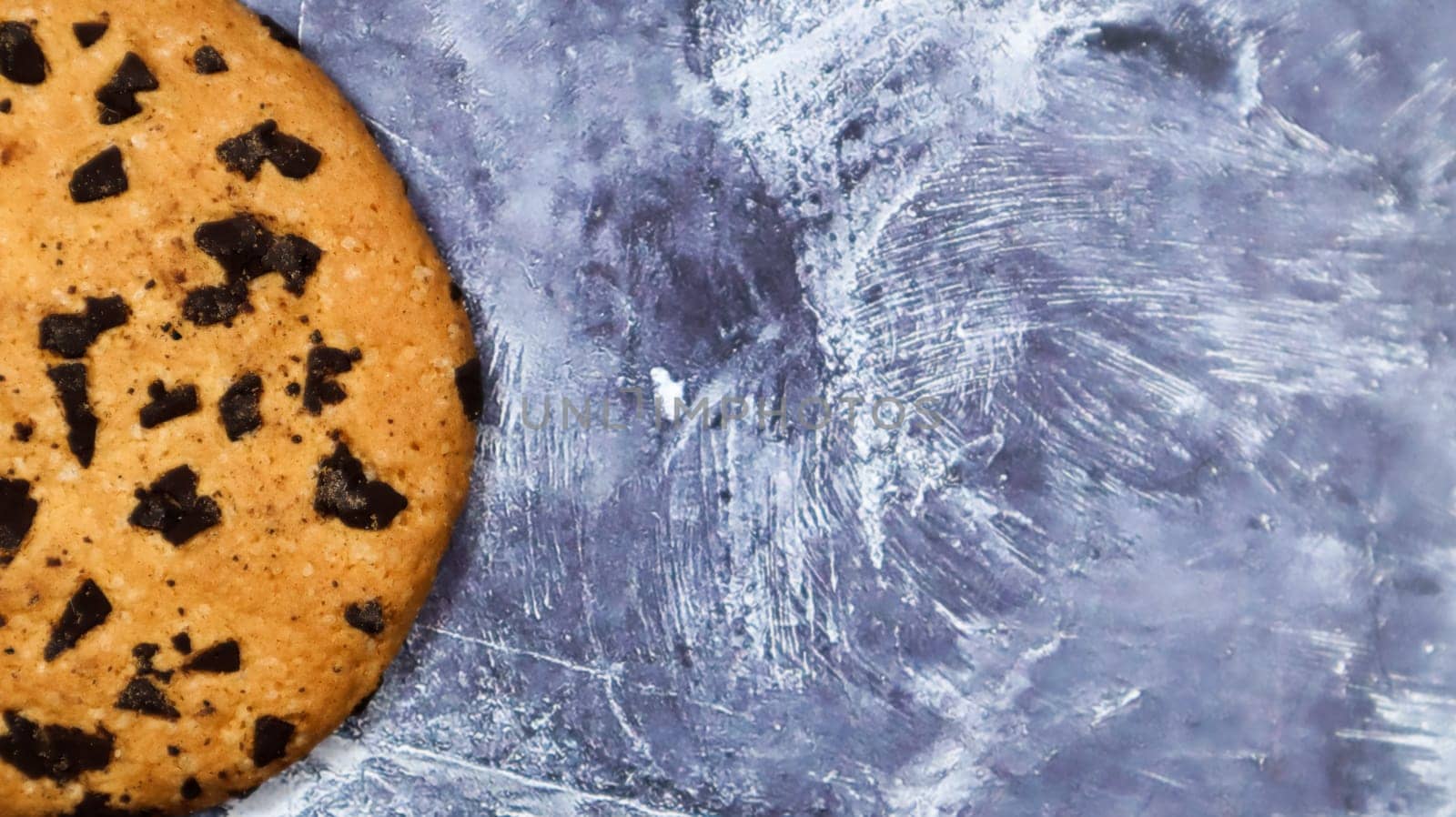 One soft, freshly baked chocolate chip cookie on a gray marble kitchen countertop. American traditional pastry, dessert. Delicious sweet food. Flat lay. Copy space.