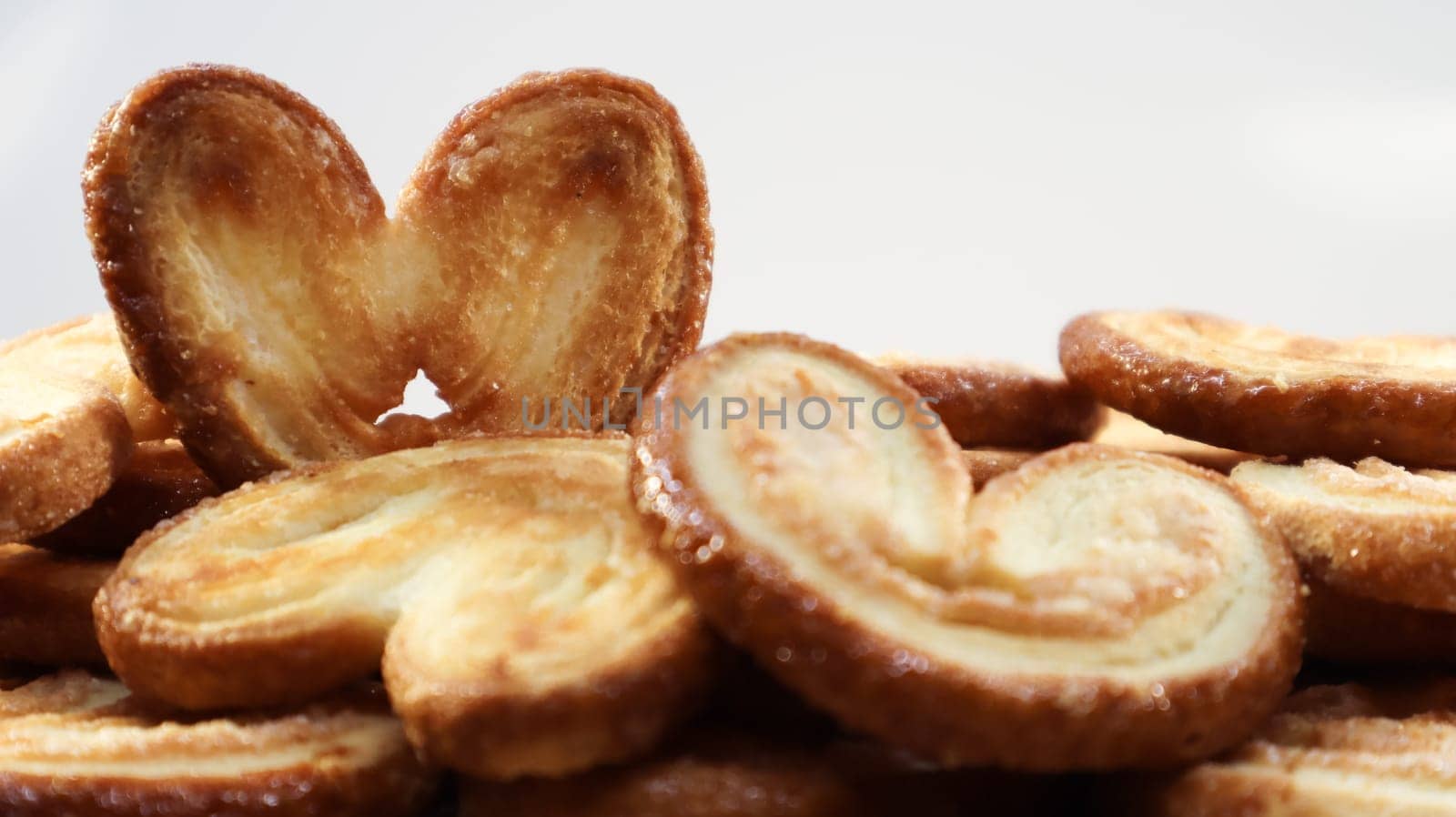 Fresh puff pastry palm cookies in the shape of a heart. Classic French pastries. Pig ear, elephant ear cookies, French hearts