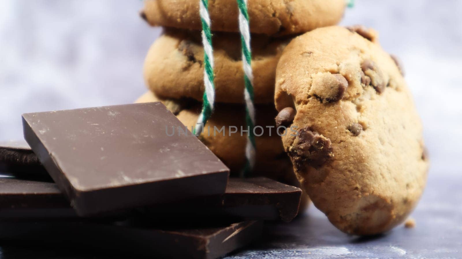 American chocolate chip cookies stacked on top of each other with green thread on a gray background. Traditional rounded crunchy dough with chocolate chips. Bakery. Delicious dessert, pastries