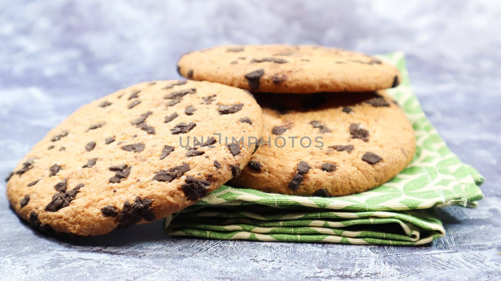 American chocolate chip cookies on a green napkin on a gray background. Traditional round crispy dough with chocolate chips. Bakery. Delicious dessert, pastries