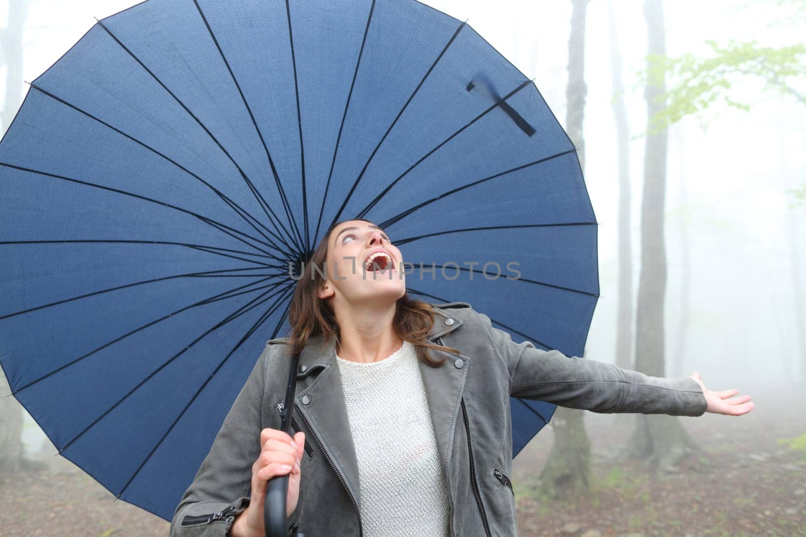 Happy woman with a big umbrella celebrating a rainy day in a park