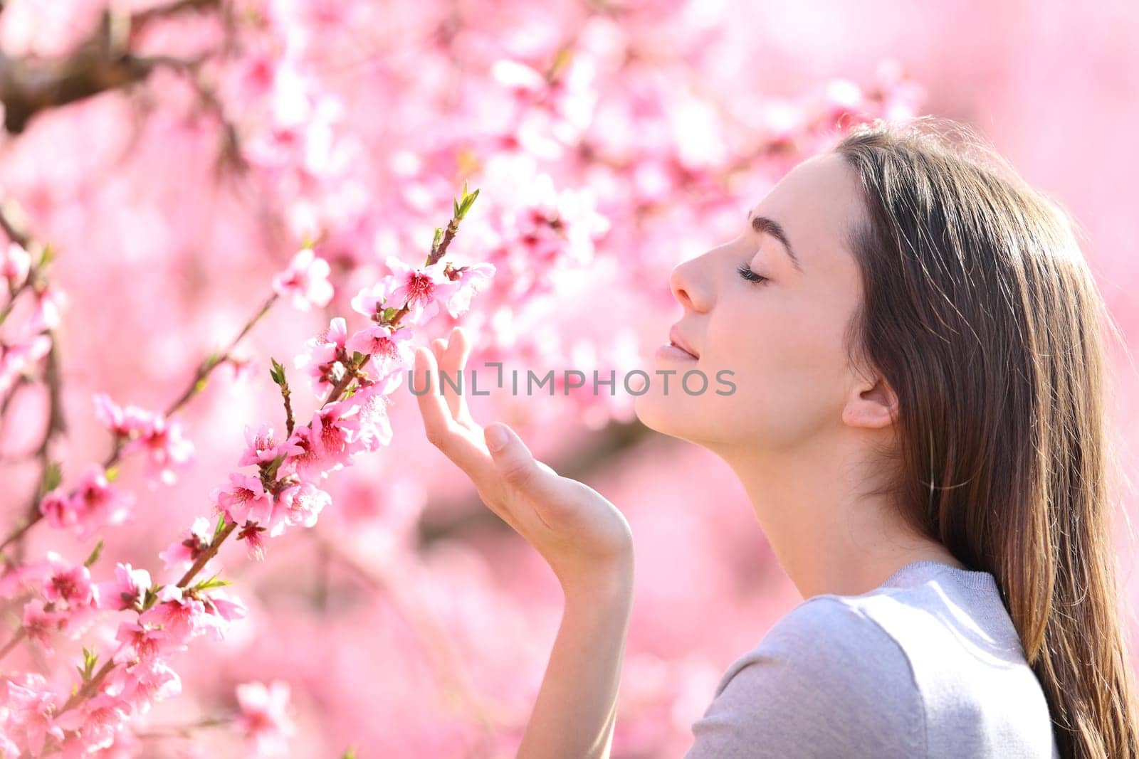 Profile of a woman smelling flowers in a pink field a sunny day