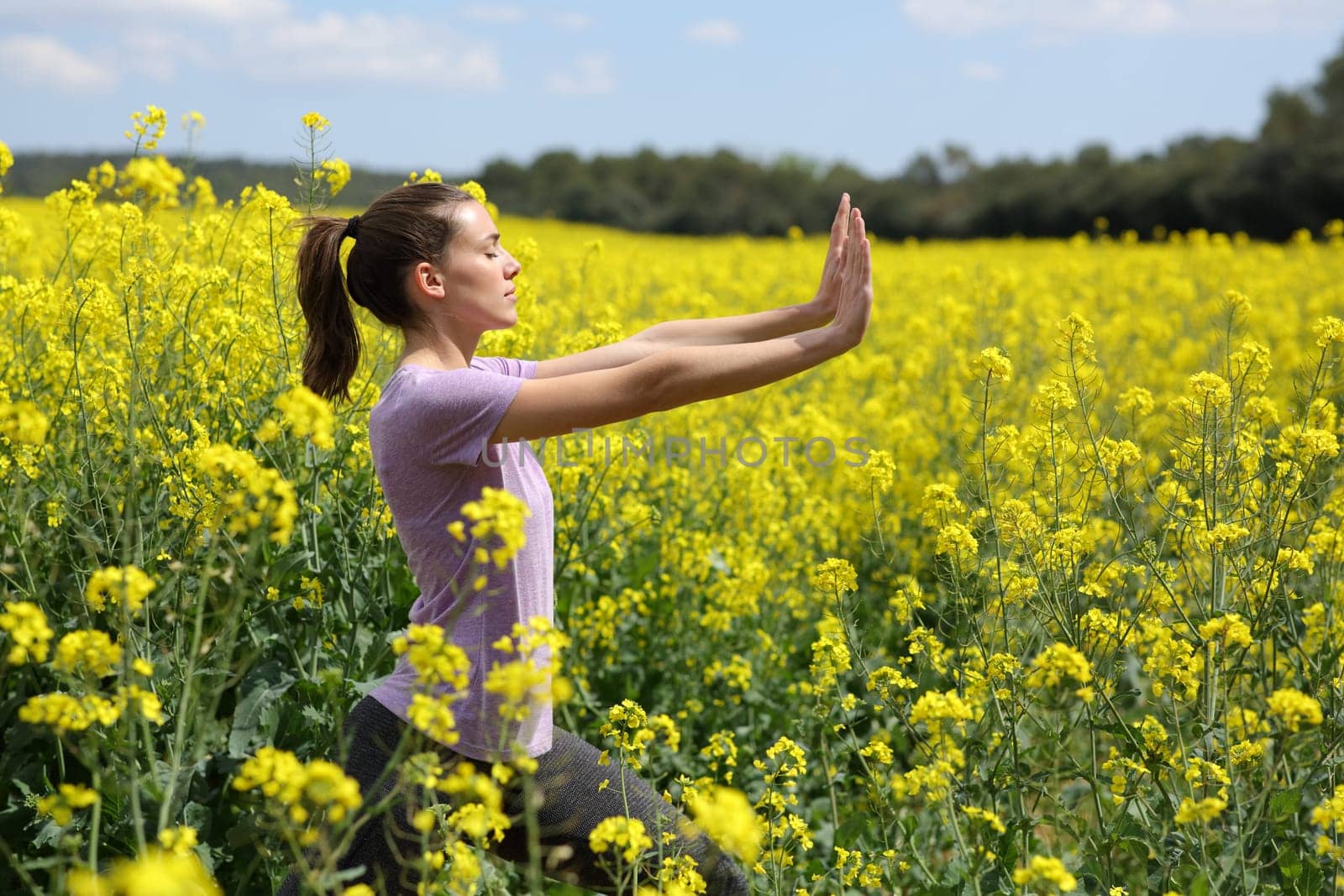 Profile of a woman doing tai chi exercise standing in a yellow field