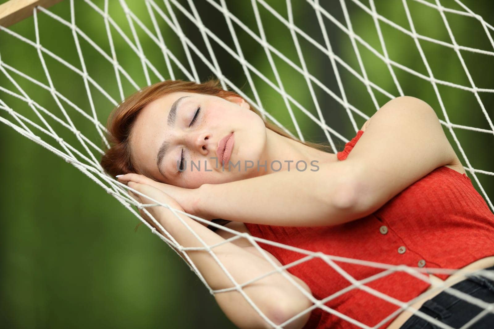 Woman relaxing sleeping on rope hammock in a garden or forest
