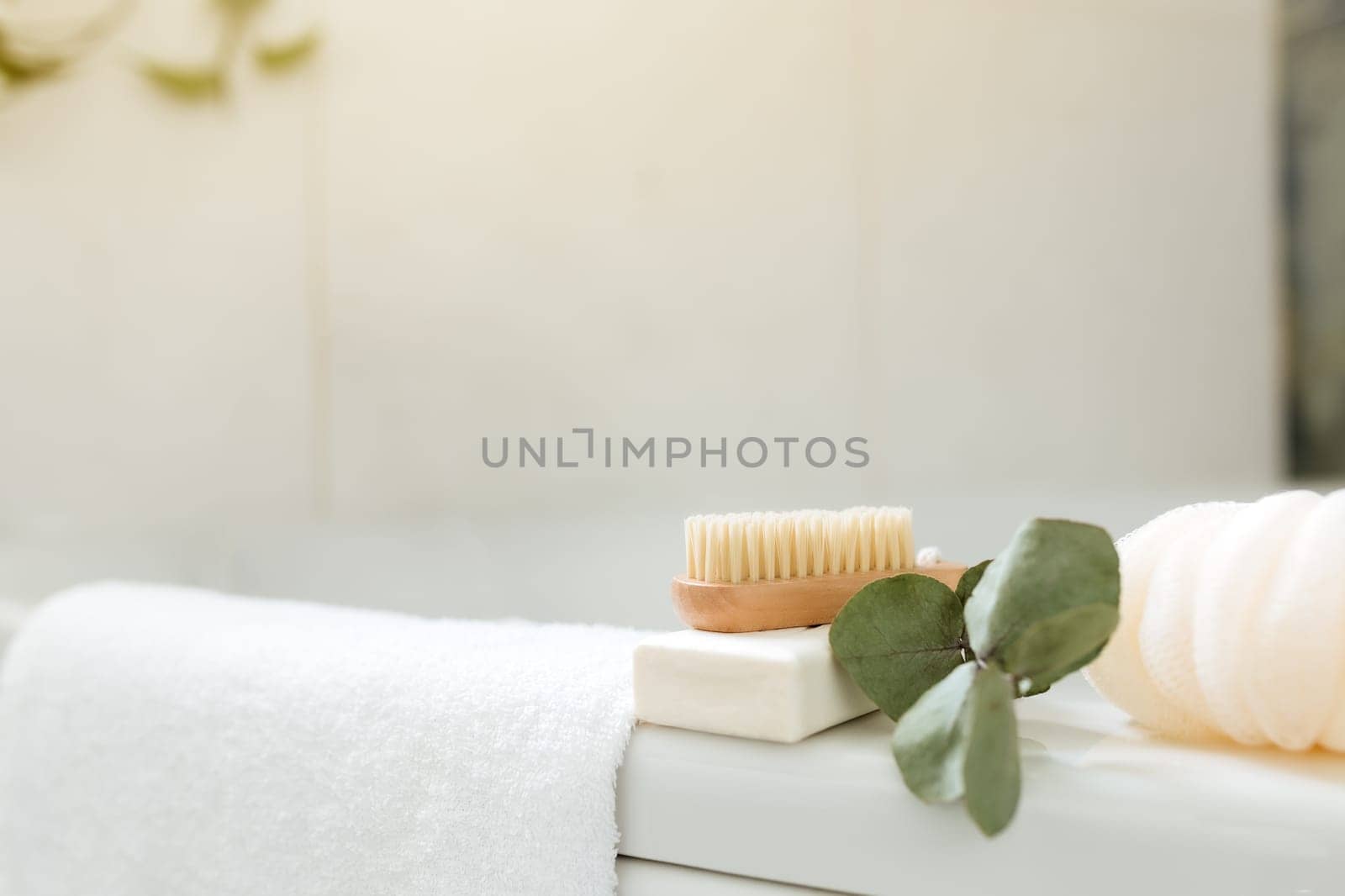 Washbasin in white bathroom with bath accessories. Hotel cleaning concept. Household concept. Washcloth, soap, foot brush, white towel and eucalyptus branch with green leaves. Stylish bathroom