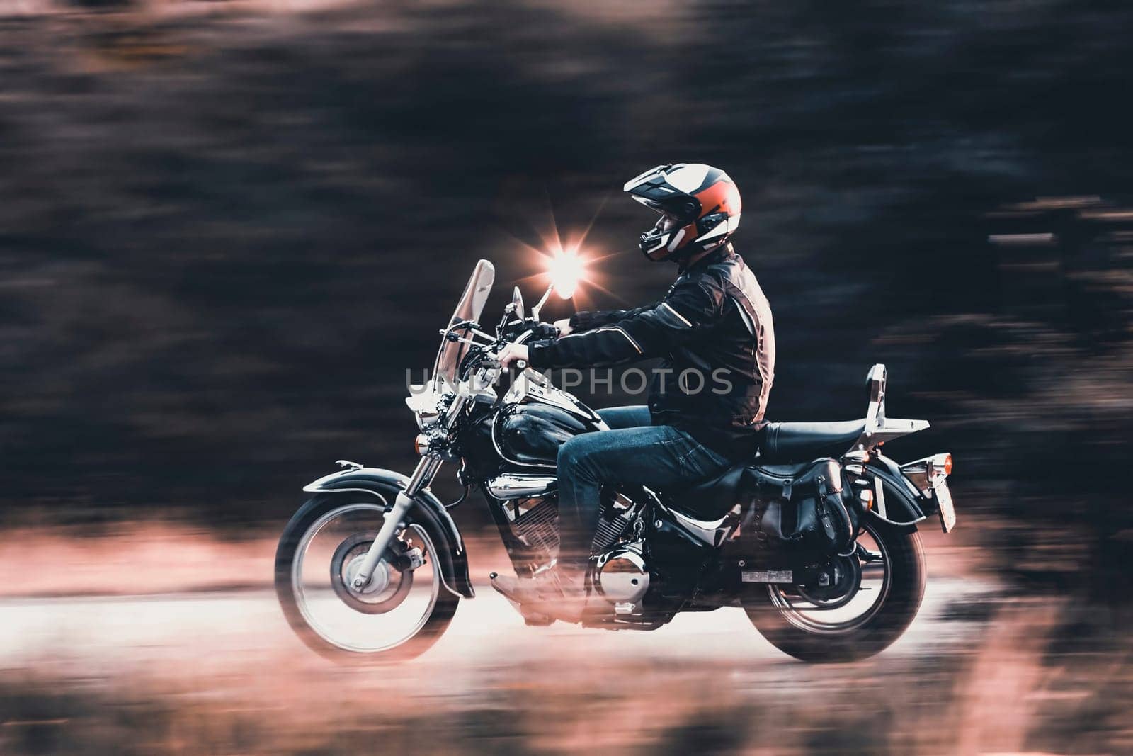 Motorcycle driver driving in beautiful sunset.