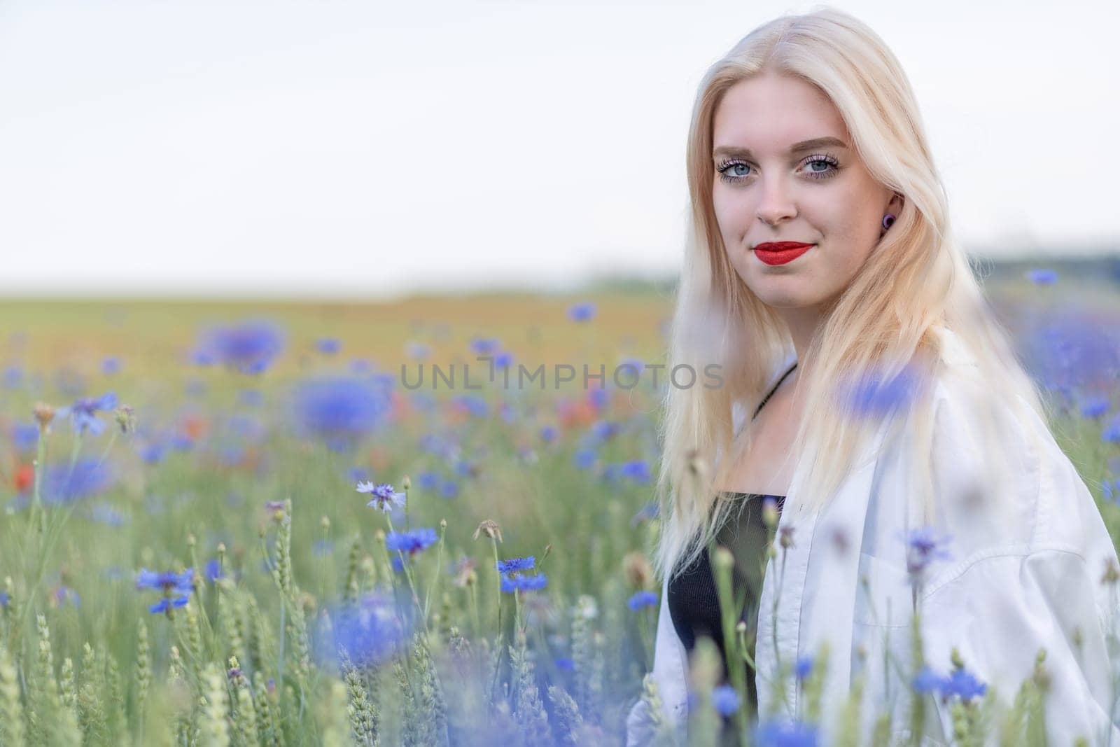 Portrait of attractive blonde woman in cornflower meadow. Horizontally.