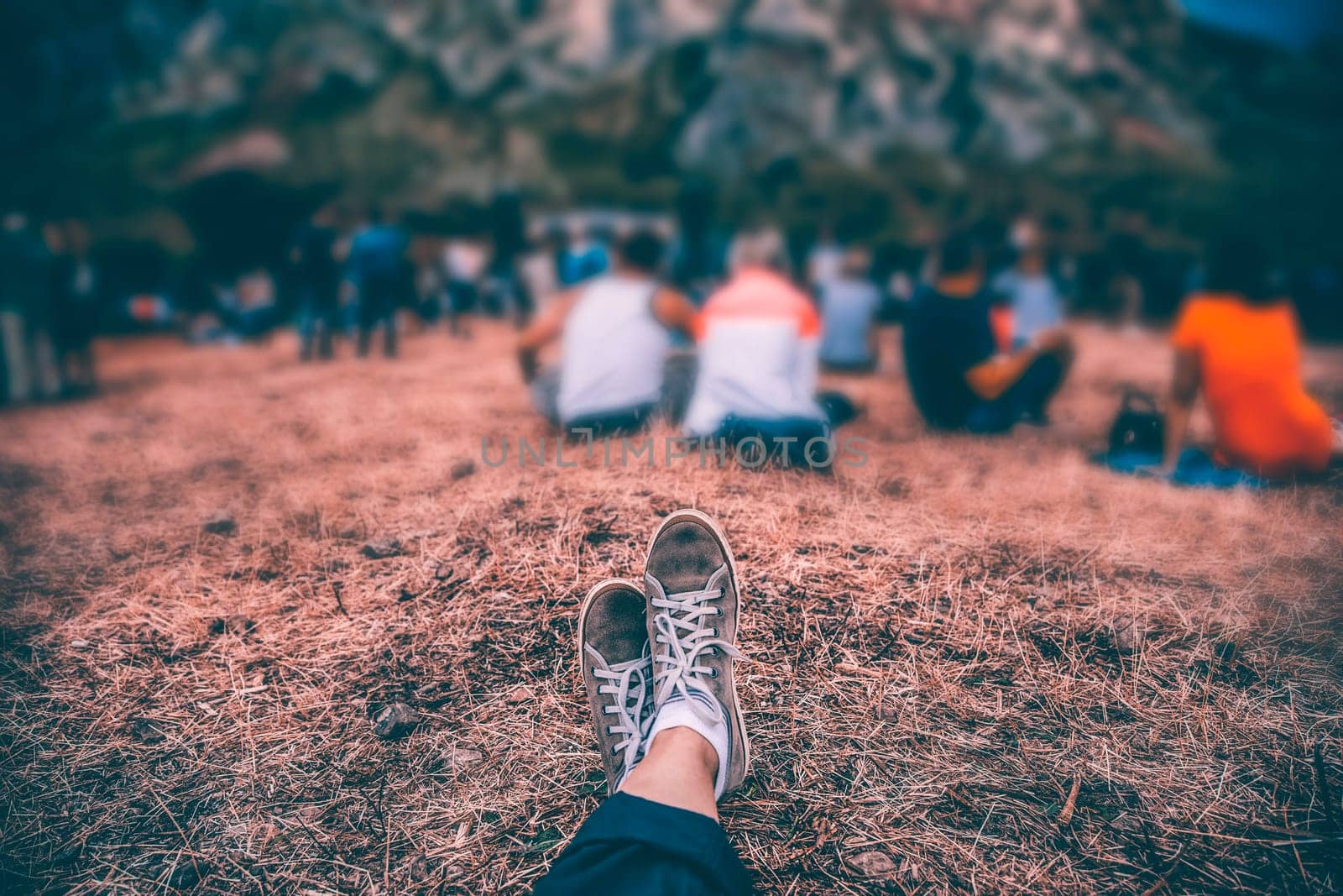 Teens at concert at summer festival. Legs of teenager at summer music festival, canvas shoes, sitting on the grass in front of stage