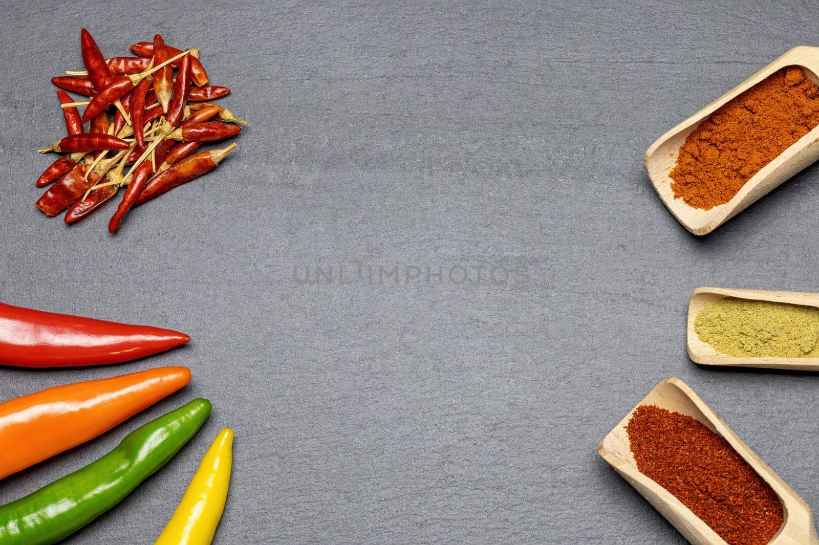 Different types of fresh, dried and ground chili on gray the desk. Horizontally.