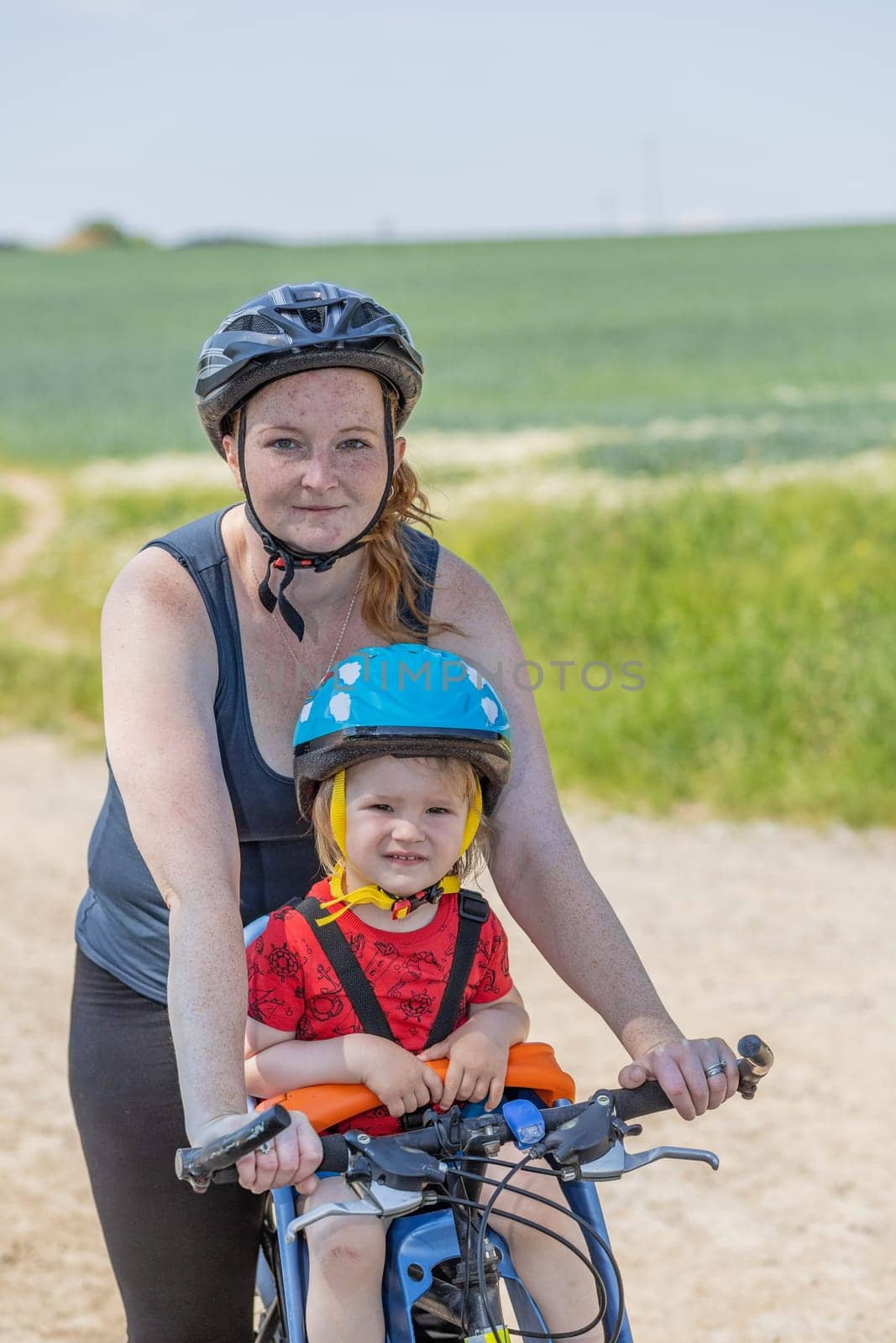 Mother is posing with her little son on the bicycle. All potential trademarks are removed.