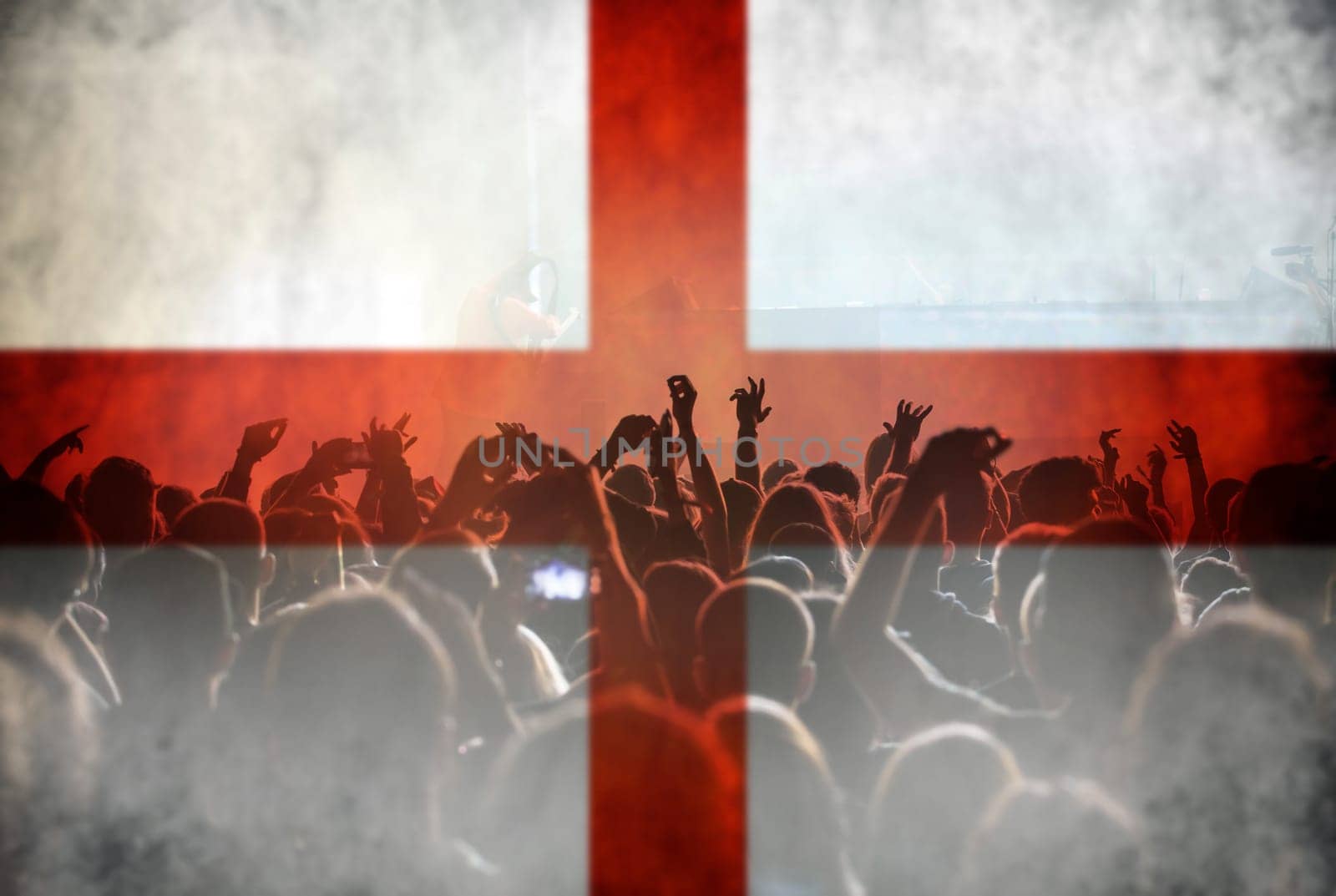Football fans supporting England - crowd celebrating in stadium with raised hands against England flag