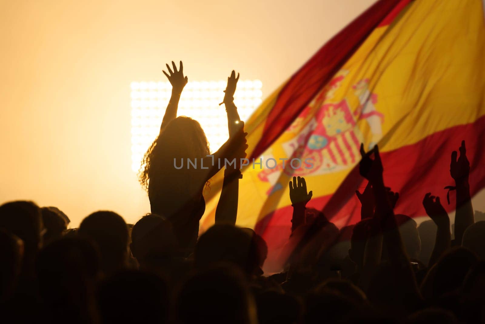 Football fans supporting Spain - crowd celebrating in stadium with raised hands against Spain flag