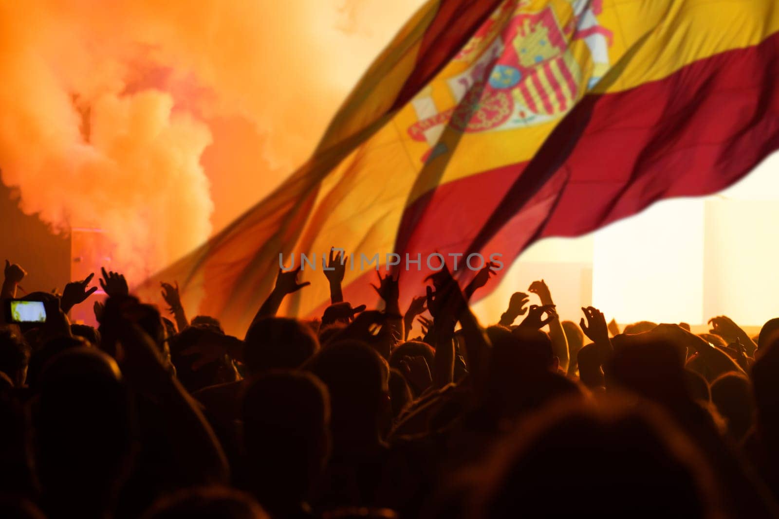 Football fans supporting Spain - crowd celebrating in stadium with raised hands against Spain flag