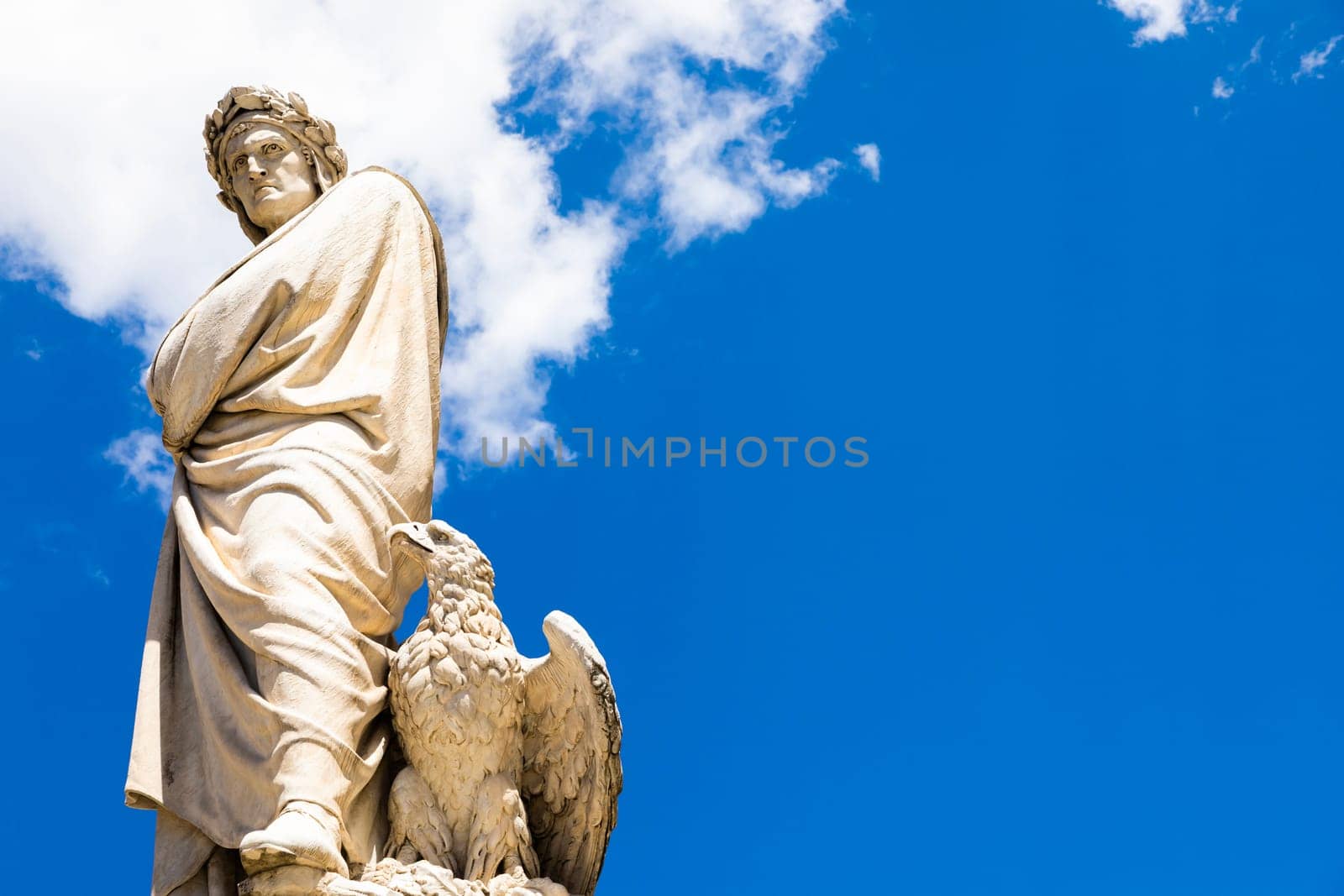 Dante Alighieri statue in Florence, Tuscany region, Italy, with an amazing blue sky background.