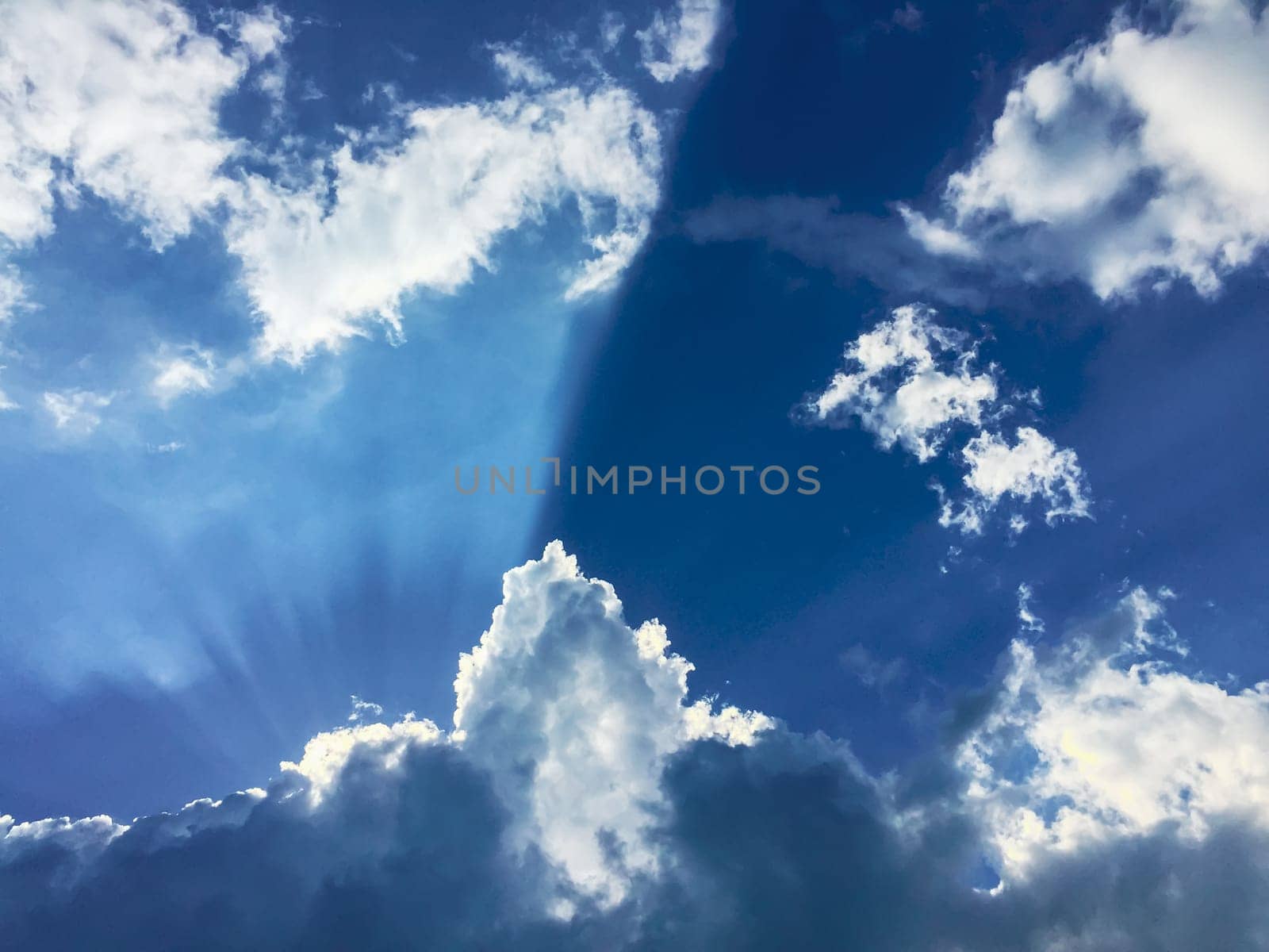 Blue cloudy sky with white clouds and rays of light