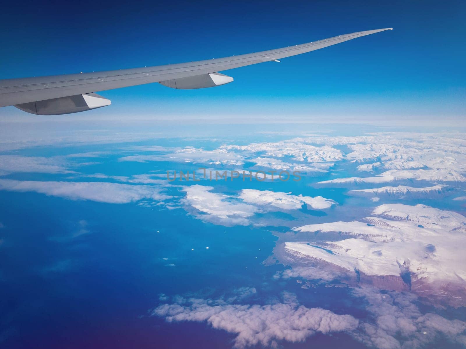View from plane above Greenland on mountains of ice and sea