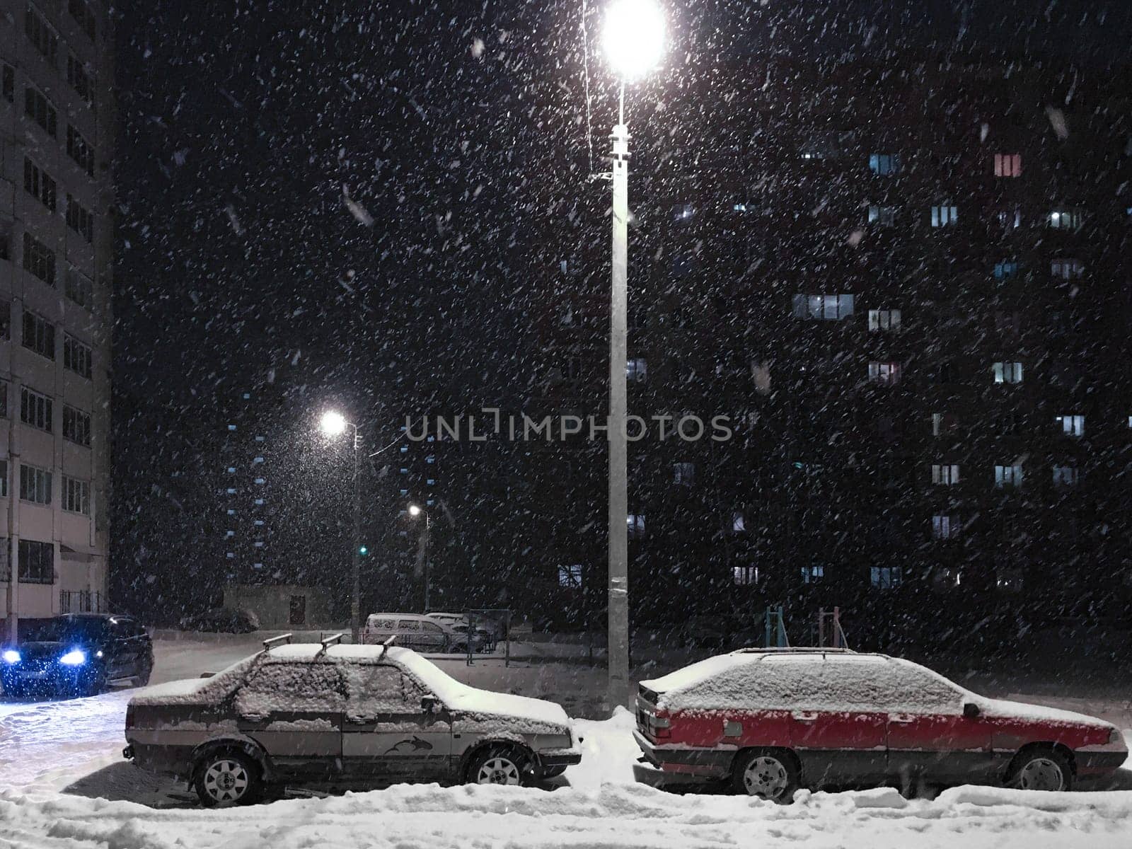 Night scene of snow storm street, blizzard with cars