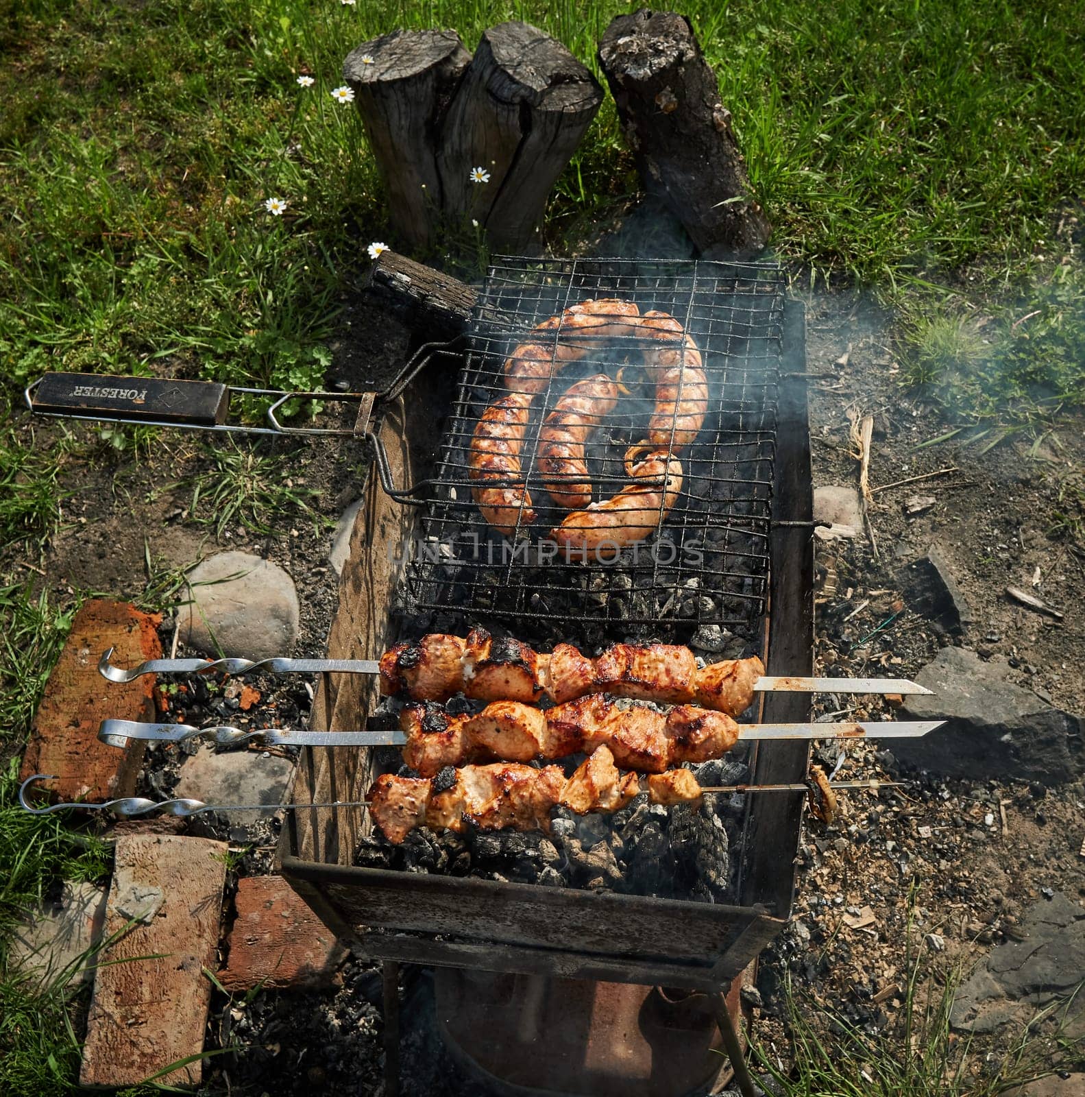 Man preparing shashlik or shish kebab over charcoal. Barbeque meat and sausages or bratwurst on a grill grate in backyard. Grilled meat on metal skewer outdoor. BBQ party or picnic food. Close up shot