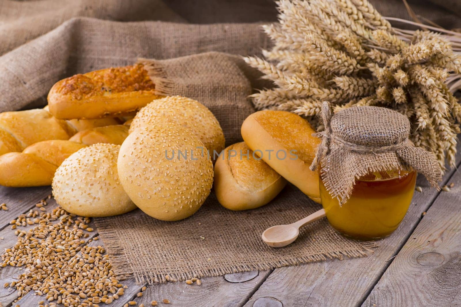Honey in a jar, slice of bread, wheat and milk on an old vintage planked wood table from above. Rural or rustic style breakfast concept. Background layout with free text space.