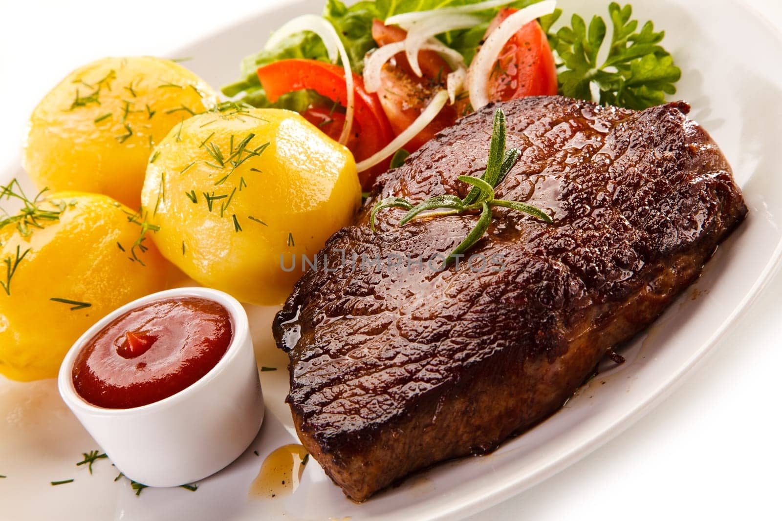 Grilled steaks, boiled potatoes and vegetable salad on white bac
