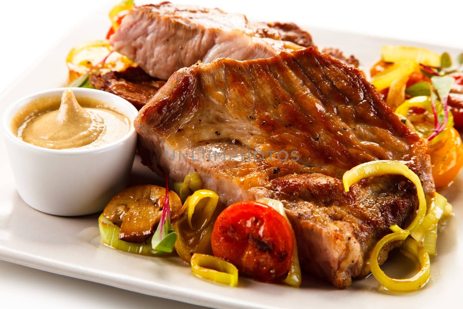 Roasted steaks with vegetables on white plate