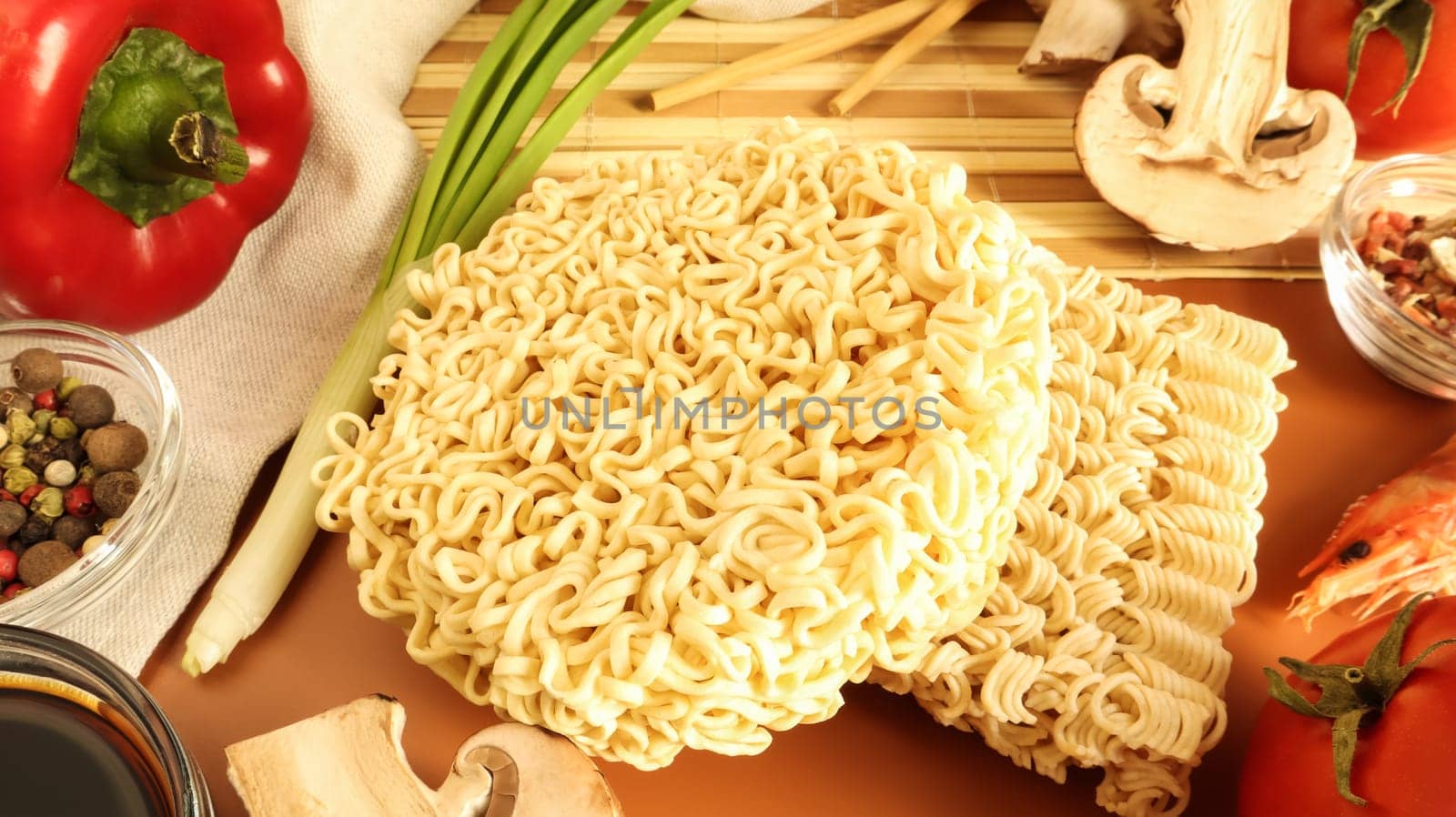 Instant noodles with king mushrooms, seasonings, soy sauce, peppers, green onions, tomatoes. Vegetable fast vegetarian soup. The process of cooking Asian food on the table. Vermicelli, spaghetti.
