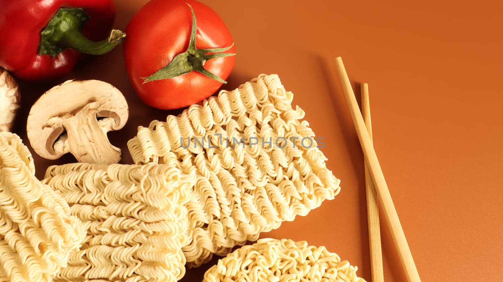 Instant noodles with king mushrooms, seasonings, soy sauce, peppers, green onions, tomatoes. Vegetable fast vegetarian soup. The process of cooking Asian food on the table. Vermicelli, spaghetti.