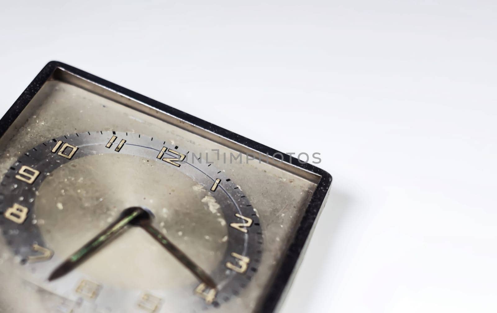 Old worn clock with square dial isolated on a white background. Analog time measurement. Vintage and retro object. Copy space.
