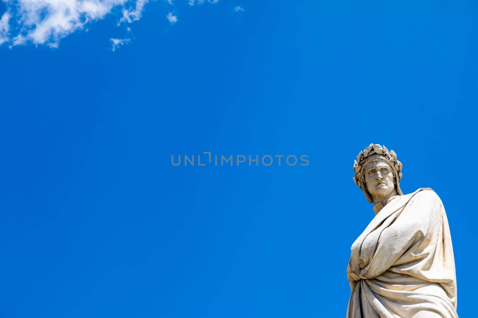 Dante Alighieri statue in Florence, Tuscany region, Italy, with an amazing blue sky background.