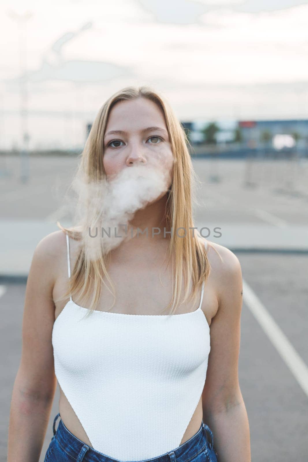 Blonde woman in city with electronic cigar ready for vaping