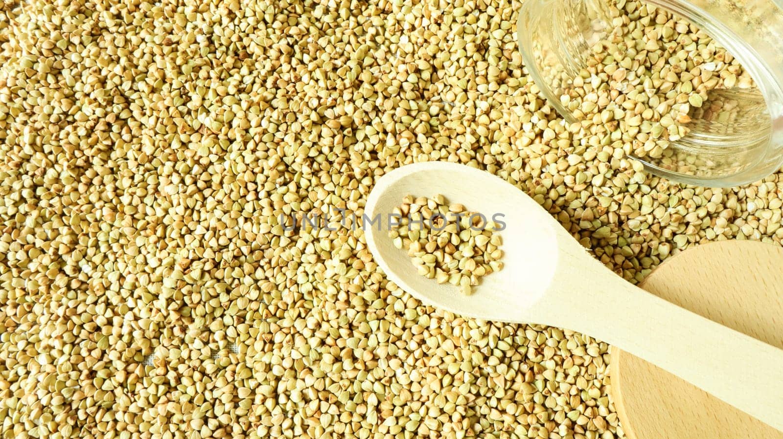 Buckwheat scattered background, raw green cereal in a wooden spoon. Healthy groats. Organic raw non-fried vegetarian food. The concept of a healthy and balanced diet. Diet product. healthy groats