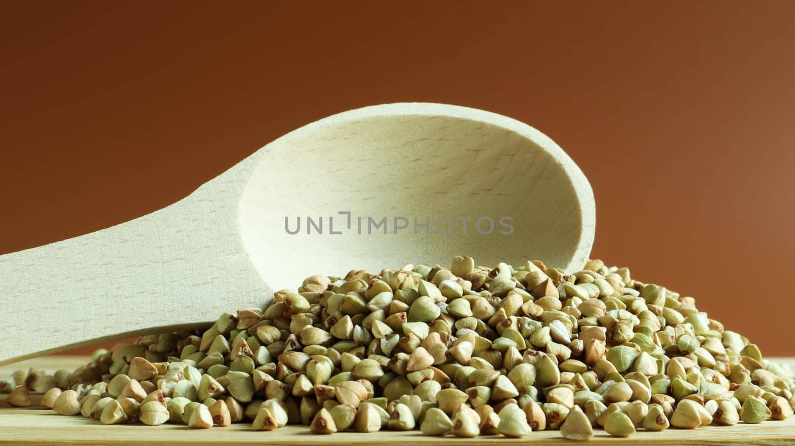 Buckwheat scattered background, raw green cereal in a wooden spoon. Healthy groats. Organic raw non-fried vegetarian food. The concept of a healthy and balanced diet. Diet product. healthy groats.