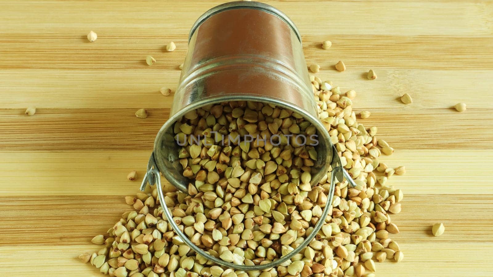Small metal bucket with raw buckwheat on a board on a brown background. Organic vegetarian food. The concept of a healthy and balanced diet. Dietary nutrition. Copy space. Top view