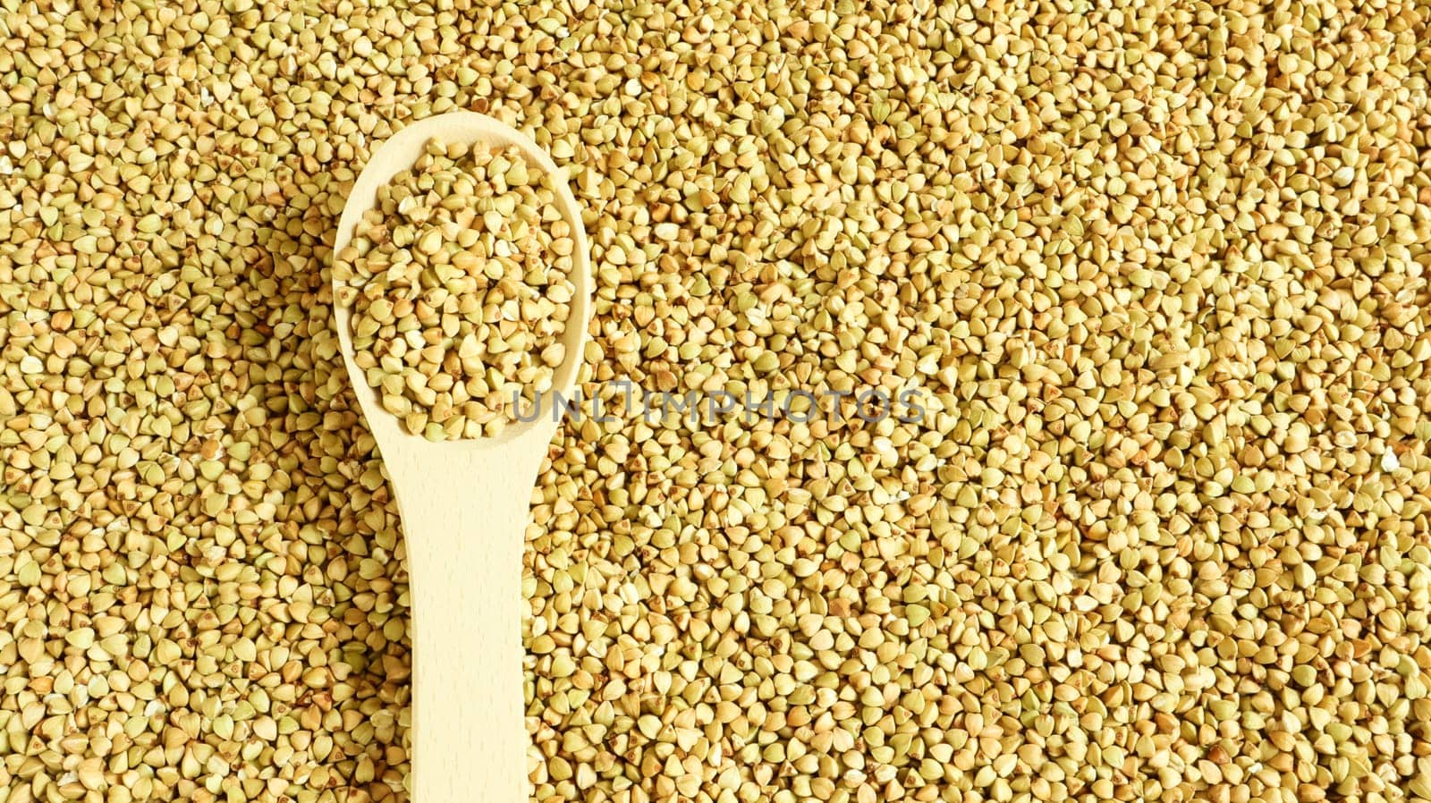 Buckwheat scattered background, raw green cereal in a wooden spoon. Healthy groats. Organic raw non-fried vegetarian food. The concept of a healthy and balanced diet. Diet product. healthy groats