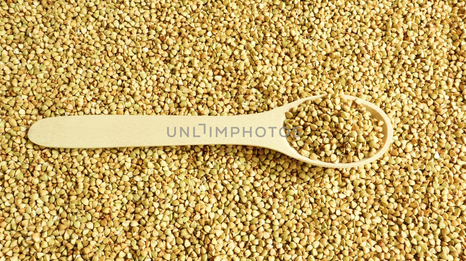 Buckwheat scattered background, raw green cereal in a wooden spoon. Healthy groats. Organic raw non-fried vegetarian food. The concept of a healthy and balanced diet. Diet product. healthy groats