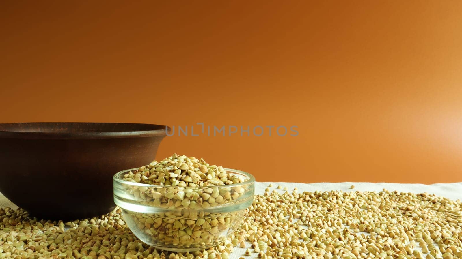 Green buckwheat in a glass transparent bowl on a brown background. healthy groats. Organic raw non-fried vegetarian food. The concept of a healthy and balanced diet. Diet Food. Copy Space.