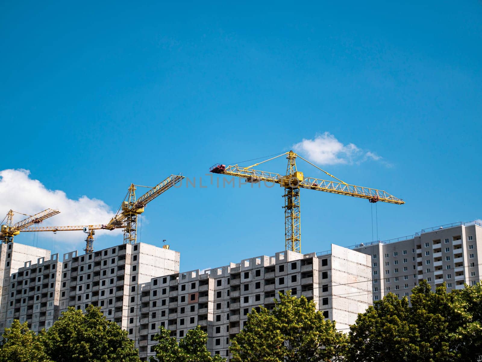 House construction with construction cranes on a background of blue sky. Construction and repair. Industry. Building sector. Poster. Advertising. Place for text. Template. Background image.